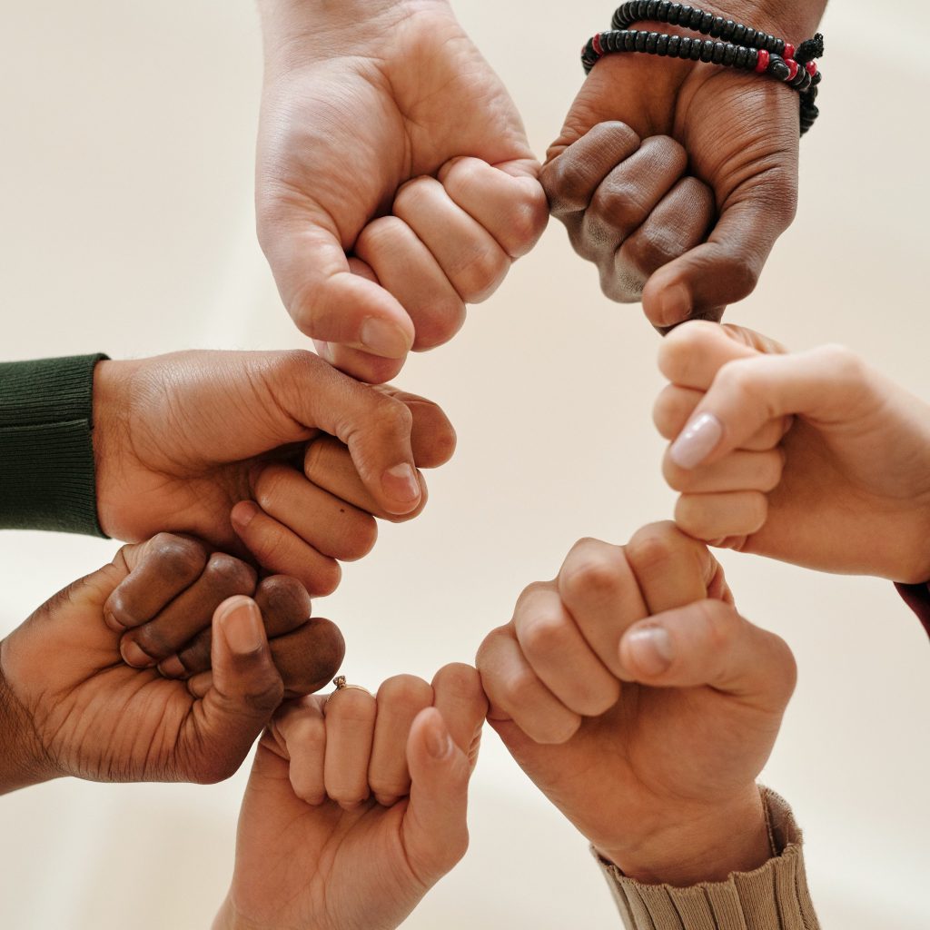 Seven fisted hands touching together to make a circle to signify coming together in support of each other. 