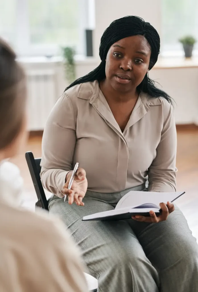 Confident psychotherapist in casualwear giving advice to young female patient at psychological session while sitting in front of her