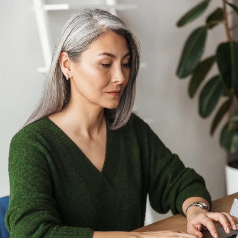 Photo of gray-haired focused businesswoman typing on laptop