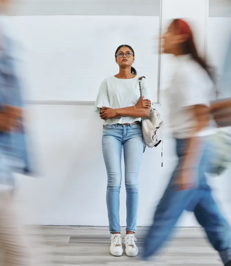 Student, anxiety and woman in busy college campus with depression, sad and mental health problems.